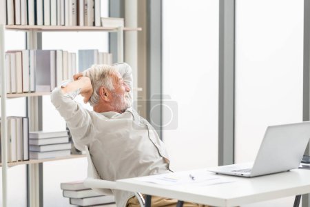 Téléchargez les photos : Heureux homme âgé à la retraite avec ordinateur portable sur la table profiter dans le salon, Homme mûr se détendre à la maison - en image libre de droit