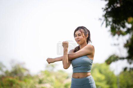 Foto de Deporte mujer calentando al aire libre, Fitness mujer en el parque haciendo ejercicio estiramiento estirar los brazos - Imagen libre de derechos