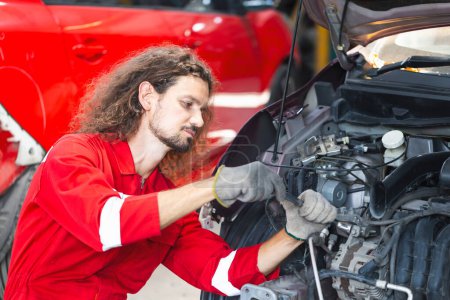 Téléchargez les photos : Homme mécanique travaillant dans le garage, Jeune mécanicien voiture de réparation dans l'atelier de réparation automobile - en image libre de droit