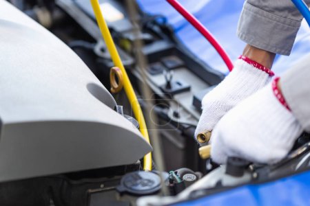 Téléchargez les photos : Technicien homme vérifie la recharge de réfrigérant de système de climatisation de voiture, réparateur avec outil de moniteur pour vérifier et réparer le système de climatiseur de voiture, réparation de climatisation de voiture - en image libre de droit