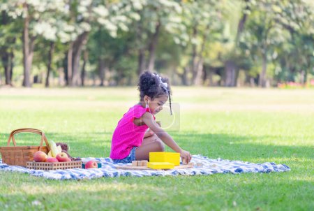 Photo for A cute little kid girl play a toy in the garden, Child girl playing with a little wooden toy outdoor - Royalty Free Image