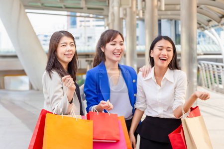 Foto de Grupo de mujeres asiáticas jóvenes que llevan bolsas de compras mientras caminan por la calle. Vida feliz y conceptos de compras - Imagen libre de derechos