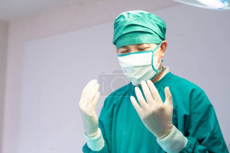 Photo for Male surgeon wearing medical protective gloves and surgical mask in operation theater at hospital, Medical team performing surgical operation in operating room - Royalty Free Image