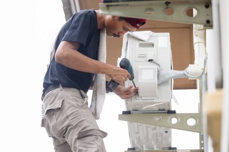 Téléchargez les photos : Technicien homme utilisant un tournevis pour réparer moderne climatiseur, réparation et entretien, Entretien, et réparer des concepts - en image libre de droit