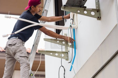 Téléchargez les photos : Technicien homme installer le système de climatisation de tuyau de vidange d'eau, réparer l'entretien et installer de nouveaux concepts de climatiseur - en image libre de droit