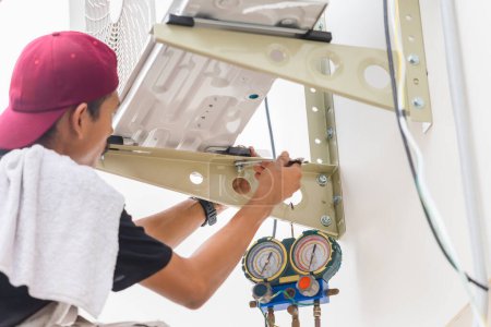 Téléchargez les photos : Technicien homme utilisant une clé pour réparer et installer un nouveau climatiseur, service de technicien masculin pour la réparation et l'entretien des climatiseurs - en image libre de droit