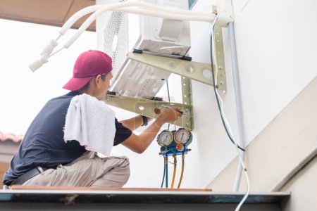 Téléchargez les photos : Service de réparateur pour la réparation et l'entretien des climatiseurs, Technicien homme installer un nouveau climatiseur - en image libre de droit