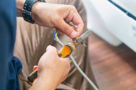 Téléchargez les photos : Technicien homme coupant des fils électriques avec des pinces pour l'installation de la nouvelle climatisation, service de réparation, et installer un nouveau concept de climatiseur - en image libre de droit