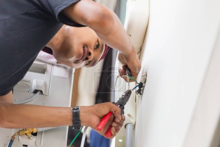 Téléchargez les photos : Technicien homme branchant des fils électriques pour installer la nouvelle climatisation, service de réparation, et installer un nouveau concept de climatiseur - en image libre de droit
