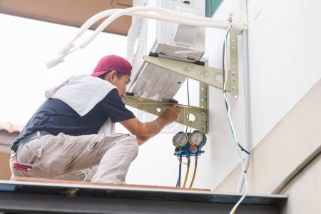 Foto de El hombre técnico instala el nuevo acondicionador de aire, servicio del reparador para la reparación y el mantenimiento de acondicionadores de aire - Imagen libre de derechos