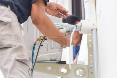 Téléchargez les photos : Équipe de techniciens installer un nouveau climatiseur, service de réparateur pour la réparation et l'entretien du climatiseur - en image libre de droit