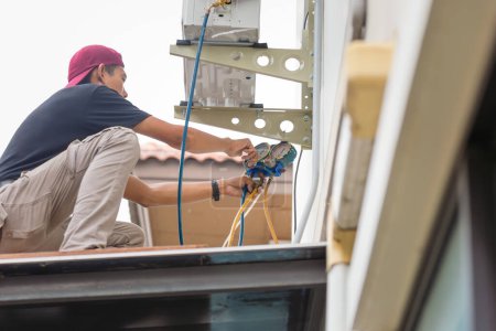 Foto de El hombre técnico instala el nuevo acondicionador de aire, servicio del reparador para la reparación y el mantenimiento de acondicionadores de aire - Imagen libre de derechos