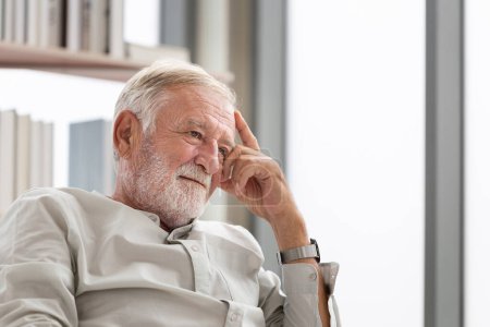 Foto de Pensando que el hombre mayor se sienta en un sofá en la sala de estar, el anciano piensa y se sienta en el sofá - Imagen libre de derechos