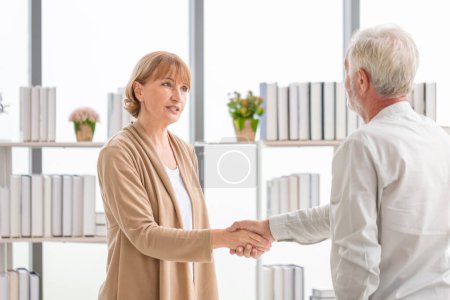 Téléchargez les photos : Femme serrant la main saluant un homme âgé client, Visiteur de santé, et un homme âgé lors d'une visite à domicile - en image libre de droit