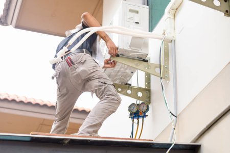 Téléchargez les photos : Service de réparateur pour la réparation et l'entretien des climatiseurs, Technicien homme installer un nouveau climatiseur - en image libre de droit