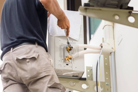 Téléchargez les photos : Technicien homme utilisant une clé pour réparer le système moderne de climatisation, Entretien, réparation et installation de nouveau climatiseur - en image libre de droit