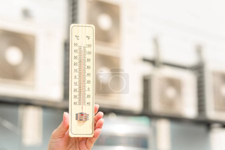 Foto de Temperatura caliente, termómetro de mano con compresor de aire acondicionado borroso - Imagen libre de derechos