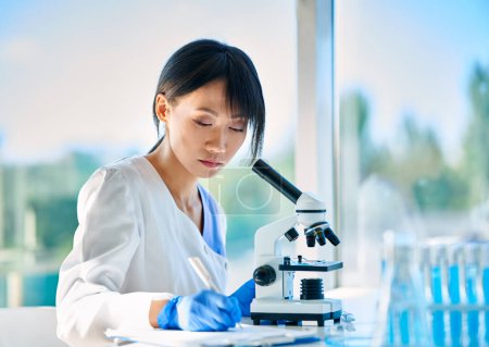 Photo for Scientist researcher working writing down analysis information at modern medical research laboratory. Medicine, biotechnology, microbiology concept - Royalty Free Image