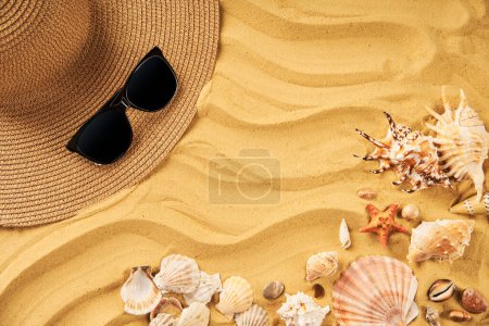 Photo for Summer time vacation concept. Straw hat, sunglasses and seashells on the sand beach with copy space for text. Flat lay, top view - Royalty Free Image