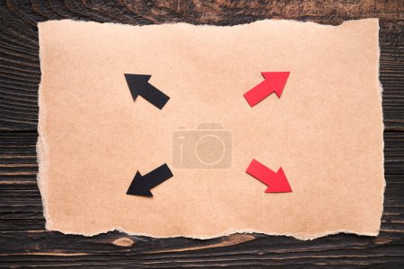 Color arrows on ripped piece of paper on dark wooden background. Direction, solution, idea concept