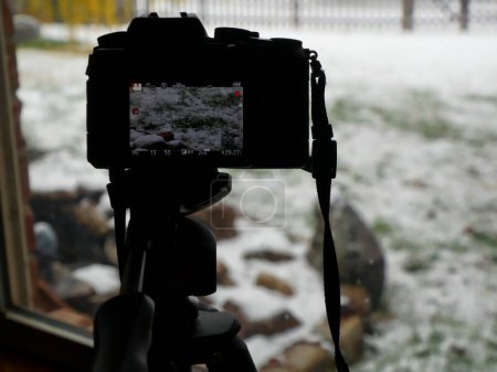 Téléchargez les photos : Close up of a camera filming a winter scene from the window - en image libre de droit