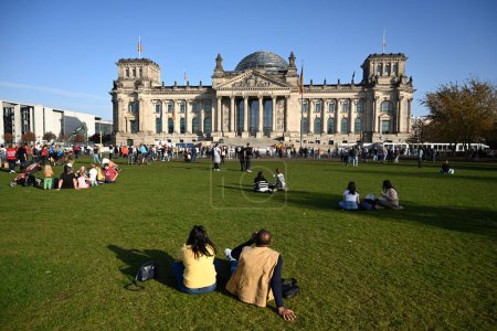 Foto de Berlín, Alemania - 31 de octubre de 2022: La gente se relaja en el gras cerca del Bundestag alemán (edificio del Reichstag) es el parlamento nacional de la República Federal de Alemania. - Imagen libre de derechos
