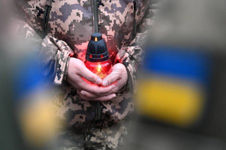 Photo for A Ukrainian seviceman holds a candle. Ukrainian flag on military uniform. Candle in hands of Soldier - Royalty Free Image