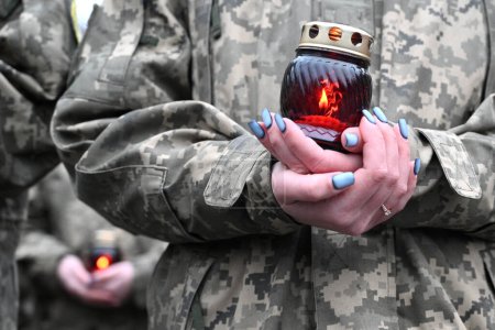 Foto de Seviceman ucraniano sostiene una vela. Vela en las manos del soldado - Imagen libre de derechos