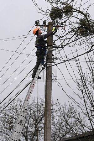 Photo for Velyka Vilshanytsia, Ukraine - March 9, 2023: A worker repairs a power line following a Russian missile strike in Lviv region. - Royalty Free Image