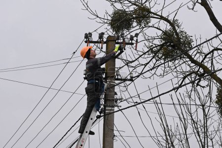 Photo for Velyka Vilshanytsia, Ukraine - March 9, 2023: A worker repairs a power line following a Russian missile strike in Lviv region. - Royalty Free Image