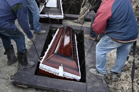 Foto de Trabajadores comunales llevan los ataúdes a las tumbas durante la ceremonia fúnebre - Imagen libre de derechos