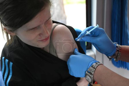 Foto de Lviv, Ucrania - 25, 2023: Una enfermera administra una vacuna COVID-19 a una niña en el punto de vacunación móvil. - Imagen libre de derechos