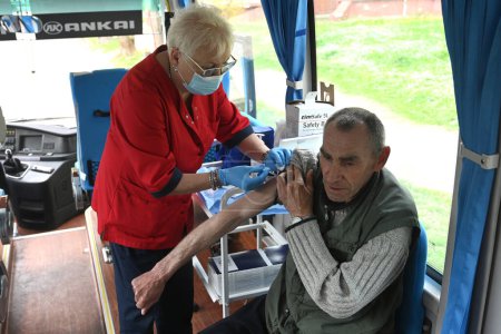 Téléchargez les photos : Lviv, Ukraine - 25, 2023 : Une infirmière administre un vaccin DCaT à un homme au point de vaccination mobile. - en image libre de droit