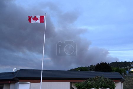 Téléchargez les photos : Les feux de forêt au Canada. La fumée d'un feu de forêt s'élève dans le ciel au-dessus de la ville - en image libre de droit