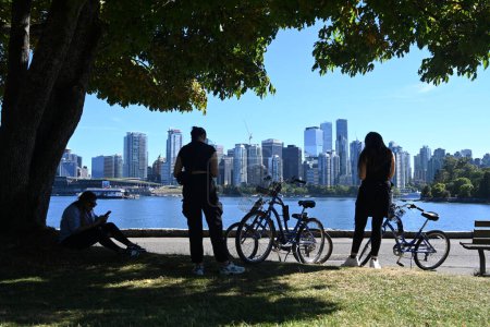 Téléchargez les photos : Vancouver, BC, Canada - 16 août 2023 : Un peuple du parc Stanley avec le centre-ville de Vancouverat à l'arrière-plan. - en image libre de droit