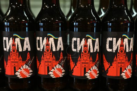 Foto de Lviv, Ucrania - 2 de abril de 2024: Una botella de cerveza local llamada Power con la etiqueta que representa un Kremlin de Moscú destruido con la bandera de Ucrania. - Imagen libre de derechos