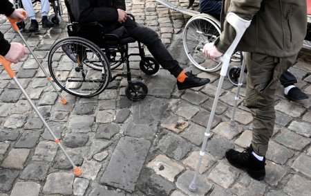 Téléchargez les photos : Un homme avec des jambes amputées dans un fauteuil roulant aux pavés. inclusivité - en image libre de droit