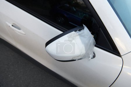 Photo for White car with crashed side mirror. Horrible self-repair with tape. Vandalism concept photo. View from above. - Royalty Free Image