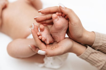 Foto de Little baby feet in mother's hands in the shape of a heart. Mom and baby. - Imagen libre de derechos
