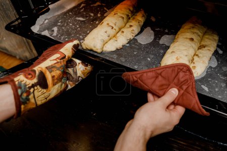 Foto de Una mujer pone una bandeja para hornear con pan tradicional alemán de Navidad Stollen en el horno. - Imagen libre de derechos
