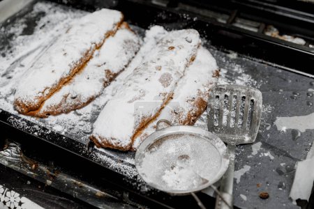 Téléchargez les photos : Pains Stollen traditionnels allemands saupoudrés de sucre en poudre sur une plaque à pâtisserie. - en image libre de droit