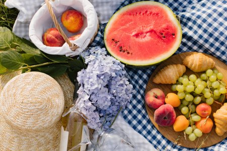 Photo for Breakfast picnic with croissants, fruits and flowers on a blanket on a sunny day. Picnic, food, brunch, summer mood. - Royalty Free Image