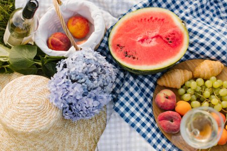 Photo for Breakfast picnic with croissants, fruits and flowers on a blanket on a sunny day. Picnic, food, brunch, summer mood. - Royalty Free Image
