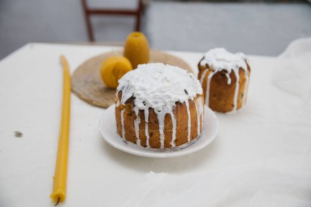 Téléchargez les photos : Deux gâteaux de Pâques avec des bougies en cire sur une table blanche. Pâques dans le village. - en image libre de droit
