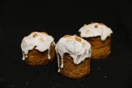 Téléchargez les photos : Gâteaux de Pâques avec glaçage blanc et noix d'amande sur fond noir. - en image libre de droit