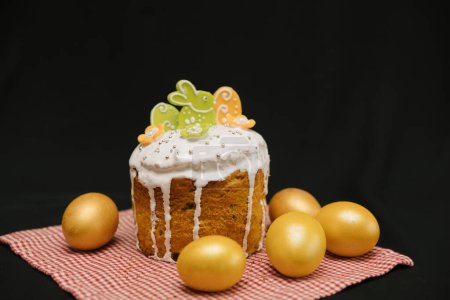 Foto de Pastel de Pascua con glaseado blanco y coloridas decoraciones y huevos amarillos sobre fondo negro. - Imagen libre de derechos