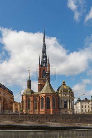 Stockholm, Schweden - 15. Juni 2022: Riddarholmen-Kirche und verzierte Kirchturmspitze mit malerischem Straßenblick