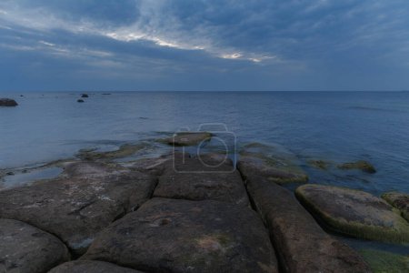 Hermosa vista a la orilla del mar con rocas cubiertas de musgo. Algas que crecen en las rocas de la costa. Hora azul