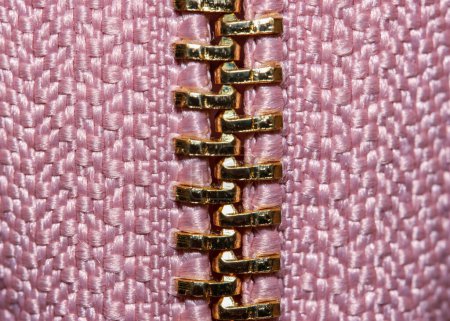 Close up view of brass zip on pink fabric.For background use.