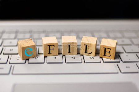 E-Datei-Text auf Holzklötzen, Konzept der Steuereinreichung durch E-Datei. Auf einer Computertastatur.